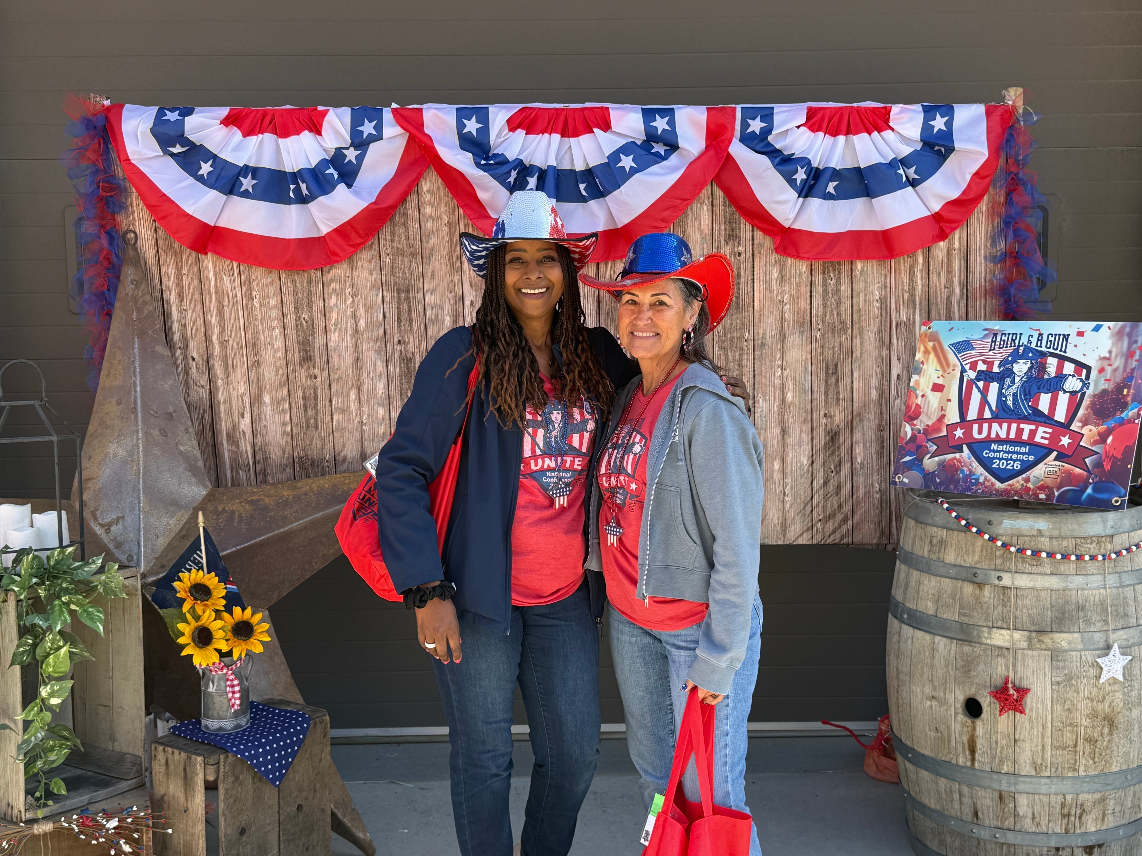 Two women at the AG&AG Unite National Conference 2026 patriotic backdrop