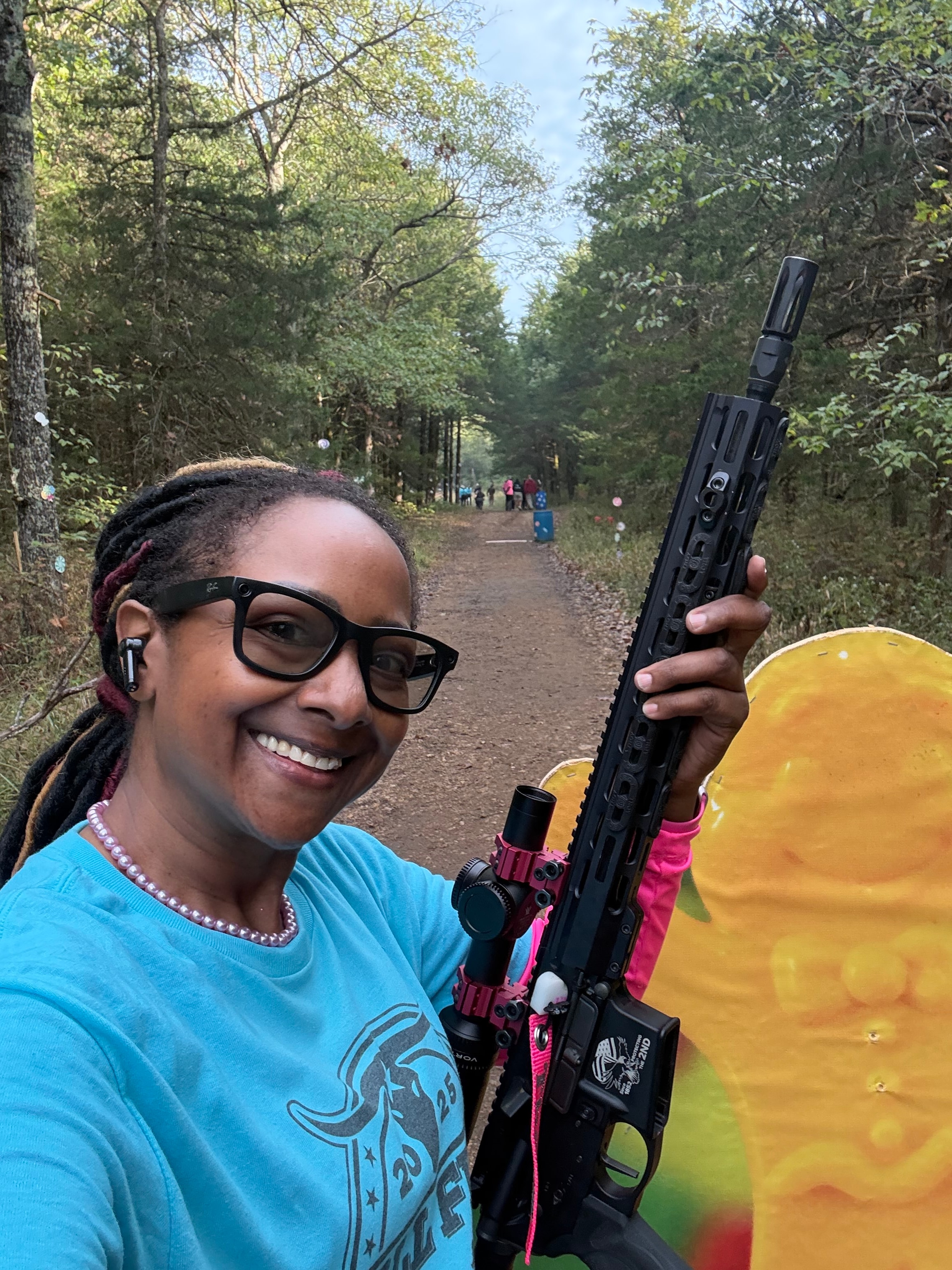Student smiling at the outdoor range holding a rifle